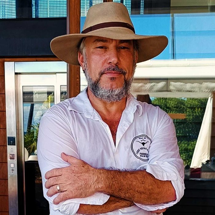 Chef Negão Maria de chapéu e camisa branca com o logo da marca